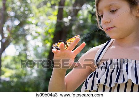 Stock Image - Girl holding monarch butterfly on finger. Fotosearch