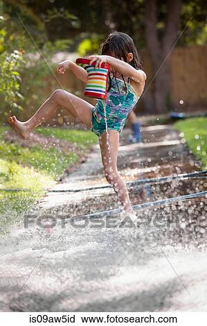 Girl holding welly, jumping over puddle of water on sidewalk View Large Photo Image Stock Image - Girl holding welly, jumping over puddle of water on sidewalk. Fotosearch