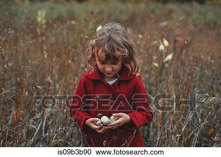 Girl holding wildflower pods in field of long grass View Large Photo Image Stock Image - Girl holding wildflower pods in field of long grass. Fotosearch