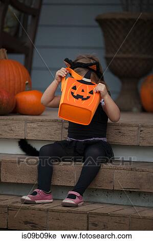 Girl in cat costume peering into trick or treating bag on porch stairway View Large Photo Image Stock Image - Girl in cat costume peering into trick or treating bag on porch stairway. Fotosearch