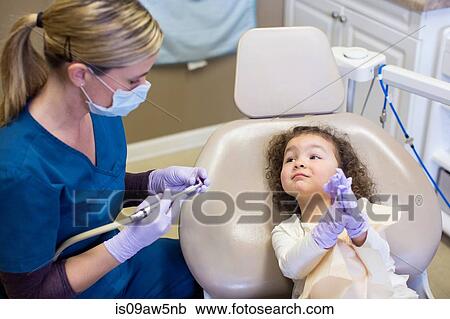 Girl in dental chair watching dentist prepare dental equipment View Large Photo Image Stock Image - Girl in dental chair watching dentist prepare dental equipment. Fotosearch