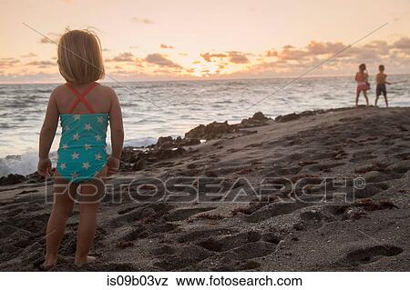 Stock Photo - Girl looking out to sea at sunrise, Blowing Rocks Preserve, Jupiter Island, Florida, USA. Fotosearch