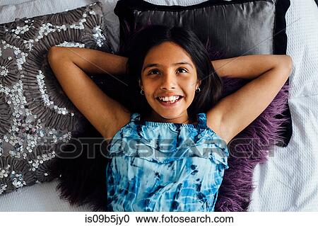 Girl lying on bed, hands behind head smiling View Large Photo Image Stock Image - Girl lying on bed, hands behind head smiling. Fotosearch