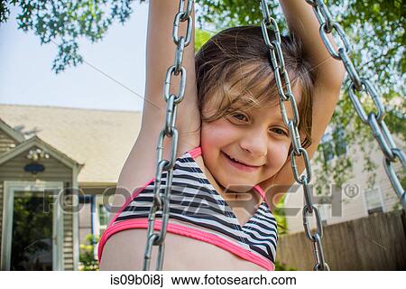 Girl playing on swing in garden View Large Photo Image Stock Image - Girl playing on swing in garden. Fotosearch