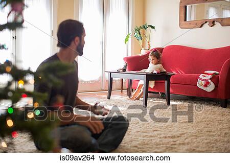 Girl sitting on sofa, father in foreground View Large Photo Image Picture - Girl sitting on sofa, father in foreground. Fotosearch