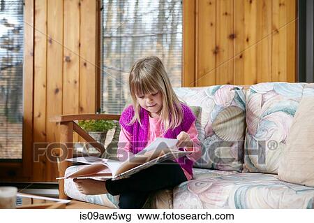 Girl sitting reading story book on living room sofa View Large Photo Image Stock Image - Girl sitting reading story book on living room sofa. Fotosearch