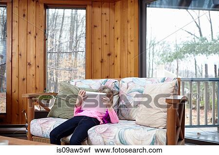 Girl slouching on living room sofa using digital tablet View Large Photo Image Stock Image - Girl slouching on living room sofa using digital tablet. Fotosearch