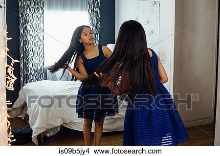 Picture - Girl wearing dress standing in front of mirror. Fotosearch