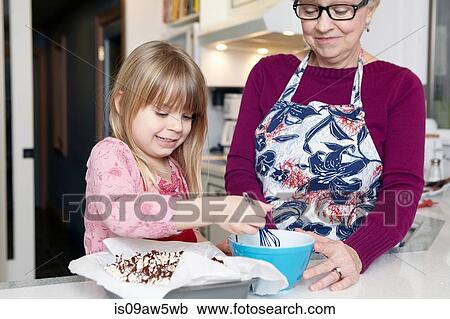 Girl whisking cake at kitchen counter with grandmother View Large Photo Image Stock Image - Girl whisking cake at kitchen counter with grandmother. Fotosearch