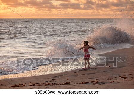 Girl with arms open whilst waves splash at sunrise, Blowing Rocks Preserve, Jupiter Island, Florida, USA View Large Photo Image Stock Photography - Girl with arms open whilst waves splash at sunrise, Blowing Rocks Preserve, Jupiter Island, Florida, USA. Fotosearch