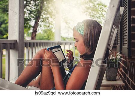 Girls on porch in rocking chair using digital tablet View Large Photo Image Stock Image - Girls on porch in rocking chair using digital tablet. Fotosearch