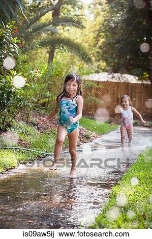 Girls running in water on sidewalk View Large Photo Image Stock Image - Girls running in water on sidewalk. Fotosearch