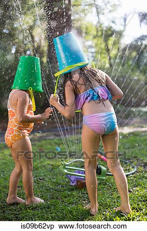 Girls with buckets on head playing with garden sprinkler View Large Photo Image Stock Photography - Girls with buckets on head playing with garden sprinkler. Fotosearch