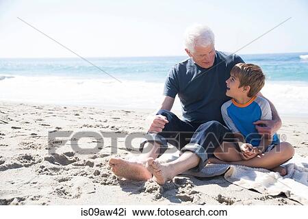 Grandfather and grandson sitting on beach, smiling View Large Photo Image Stock Image - Grandfather and grandson sitting on beach, smiling. Fotosearch