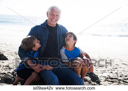 Grandfather with two grandsons, sitting on beach, smiling View Large Photo Image Stock Photo - Grandfather with two grandsons, sitting on beach, smiling. Fotosearch