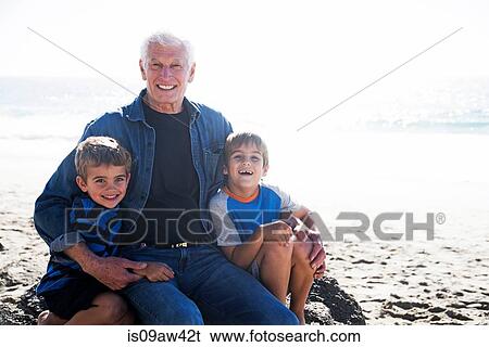 Grandfather with two grandsons, sitting on beach, smiling View Large Photo Image Stock Photograph - Grandfather with two grandsons, sitting on beach, smiling. Fotosearch