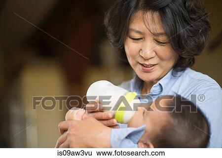 Grandmother feeding milk to grandson View Large Photo Image Stock Photograph - Grandmother feeding milk to grandson. Fotosearch