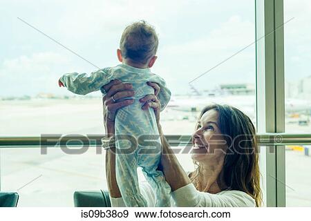 Grandmother lifting baby in mid air at airport View Large Photo Image Stock Photo - Grandmother lifting baby in mid air at airport. Fotosearch