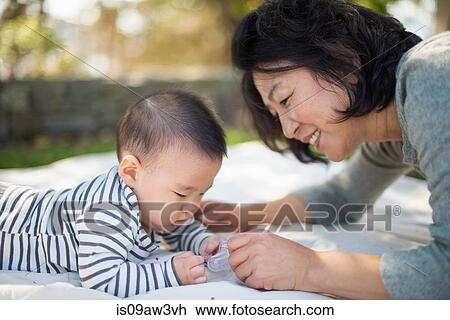 Stock Image - Grandmother playing with grandson outdoors. Fotosearch