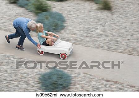 Grandmother pushing grandson on his toy car View Large Photo Image Stock Image - Grandmother pushing grandson on his toy car. Fotosearch