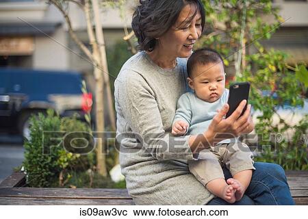 Grandmother showing smartphone to grandson outdoors View Large Photo Image Stock Image - Grandmother showing smartphone to grandson outdoors. Fotosearch