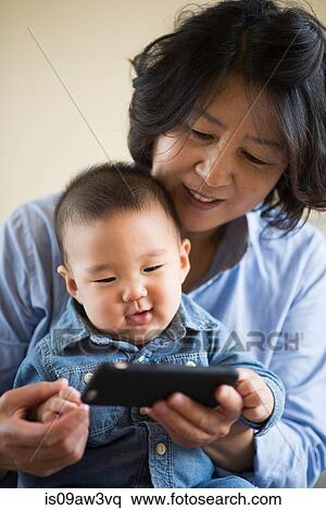Stock Photography - Grandmother showing smartphone to grandson. Fotosearch