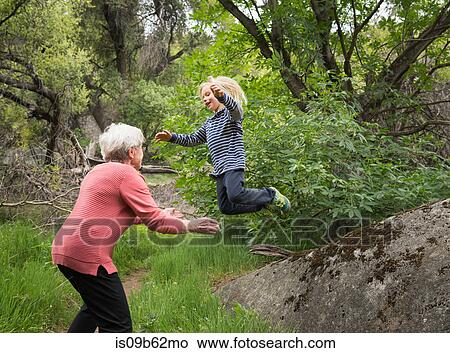 Picture - Grandson jumping off rock into grandmother's arms, Sequoia National Park, California, US. Fotosearch