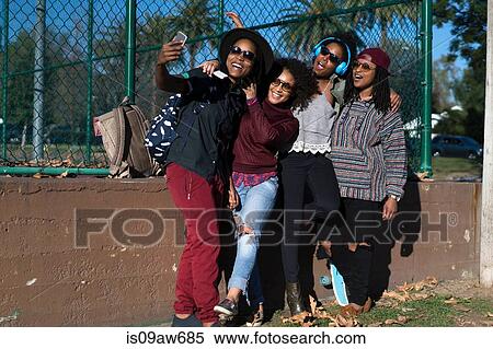 Group of female friends in park, taking self portrait, using smartphone View Large Photo Image Stock Photography - Group of female friends in park, taking self portrait, using smartphone. Fotosearch