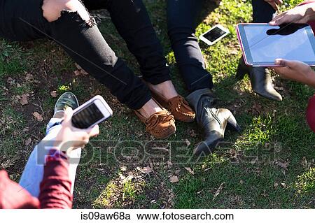 Group of female friends relaxing in park, using digital tablet and smartphone, low section View Large Photo Image Stock Image - Group of female friends relaxing in park, using digital tablet and smartphone, low section. Fotosearch