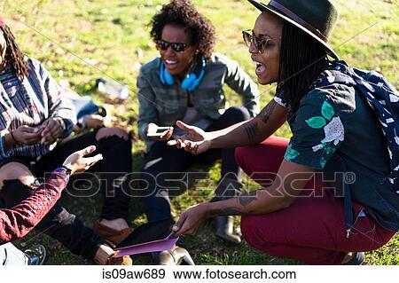 Stock Photo - Group of female friends relaxing in park, laughing. Fotosearch