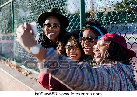 Stock Image - Group of female friends taking self portrait using smartphone. Fotosearch