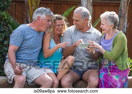 Group of seniors laughing at photos in smartphone at pool View Large Photo Image Stock Image - Group of seniors laughing at photos in smartphone at pool. Fotosearch