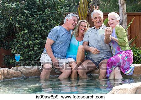 Group of seniors laughing at photos in smartphone at pool View Large Photo Image Stock Photo - Group of seniors laughing at photos in smartphone at pool. Fotosearch