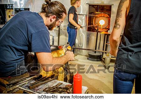 Stock Image - Group of young adults blowing glass. Fotosearch