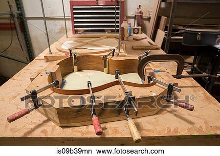 Picture - Guitar clamped in mould in workshop. Fotosearch