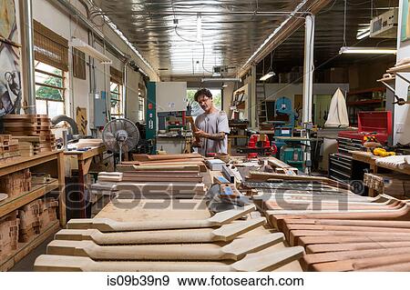 Stock Photo - Guitar maker in workshop manufacturing guitar. Fotosearch