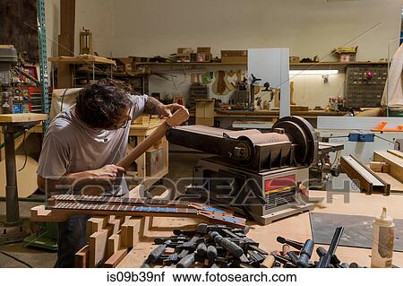 Stock Image - Guitar maker manufacturing guitar in workshop. Fotosearch