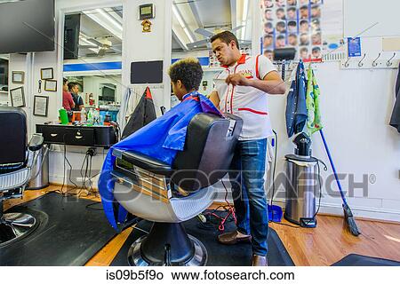 Hairdresser cutting teenage boy's hair in barbershop View Large Photo Image Picture - Hairdresser cutting teenage boy's hair in barbershop. Fotosearch