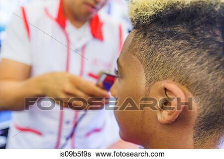 Hairdresser cutting teenage boy's hair in barbershop View Large Photo Image Stock Photograph - Hairdresser cutting teenage boy's hair in barbershop. Fotosearch