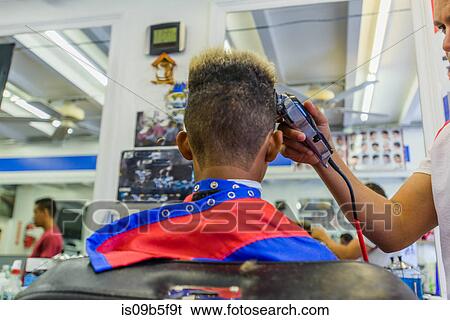 Stock Photograph - Hairdresser cutting teenage boy's hair in barbershop. Fotosearch