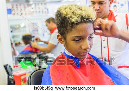 Stock Photography - Hairdresser cutting teenage boy's hair in barbershop. Fotosearch