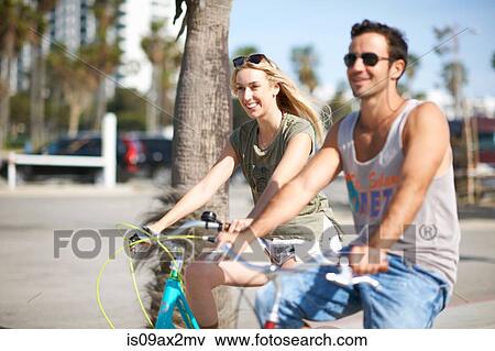 Stock Photo - Happy couple cycling together at Venice Beach, Los Angeles, California, USA. Fotosearch