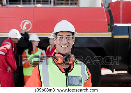 Happy engineer on oil rig, colleagues working in background View Large Photo Image Stock Image - Happy engineer on oil rig, colleagues working in background. Fotosearch