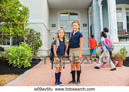 Stock Photograph - Happy girls standing in front of school. Fotosearch