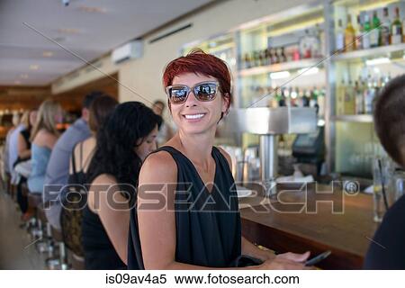 Happy mature woman looking over her shoulder from bar View Large Photo Image Stock Photography - Happy mature woman looking over her shoulder from bar. Fotosearch