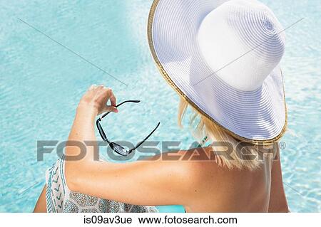 High angle rear view of young woman wearing sun hat sitting by swimming pool View Large Photo Image Stock Image - High angle rear view of young woman wearing sun hat sitting by swimming pool. Fotosearch