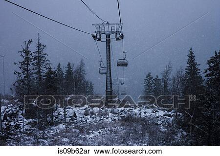 Stock Photography - High angle view of chairlift during mountain snowstorm. Fotosearch