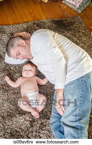 High angle view of father lying on rug next to baby girl View Large Photo Image Stock Photo - High angle view of father lying on rug next to baby girl. Fotosearch