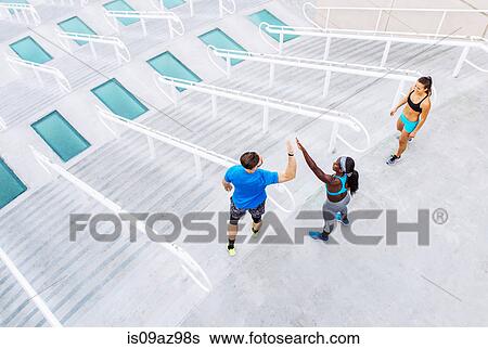Stock Photograph - High angle view of man and women training, high fiving on stairway at sport facility, downtown San Diego, California, USA. Fotosearch