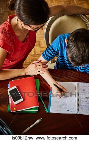 High angle view of mother at dining table helping son with homework View Large Photo Image Stock Photo - High angle view of mother at dining table helping son with homework. Fotosearch